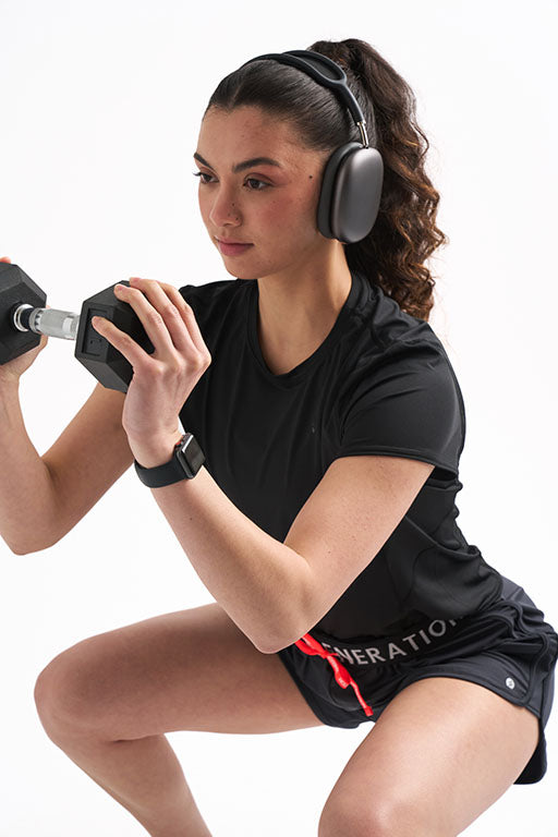 Woman lifting weights and doing a squat in athletic wear.