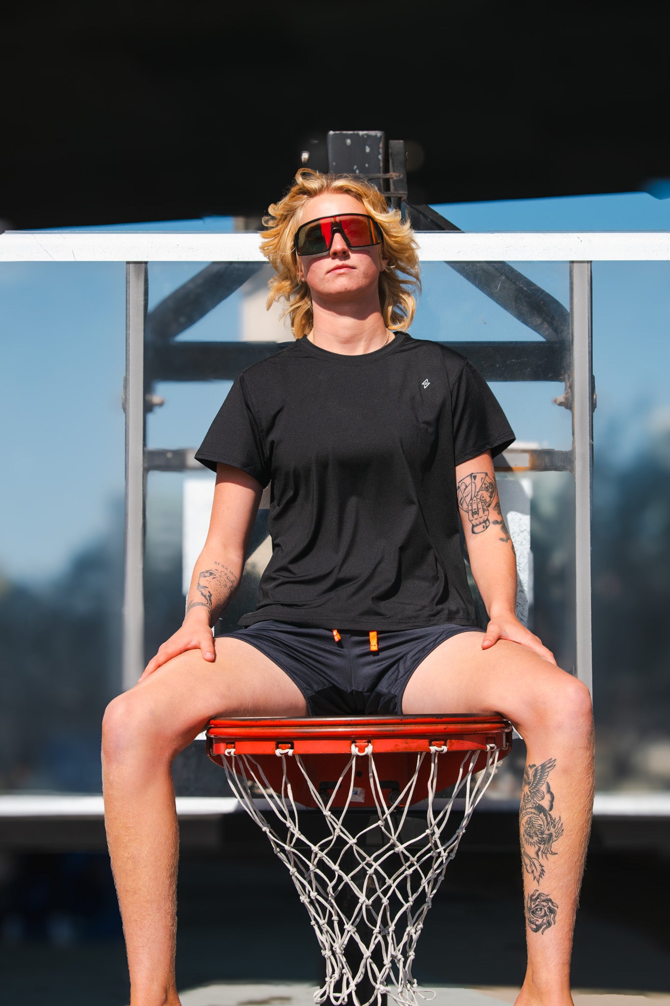 Person sitting on a basketball hoop with a blurred background