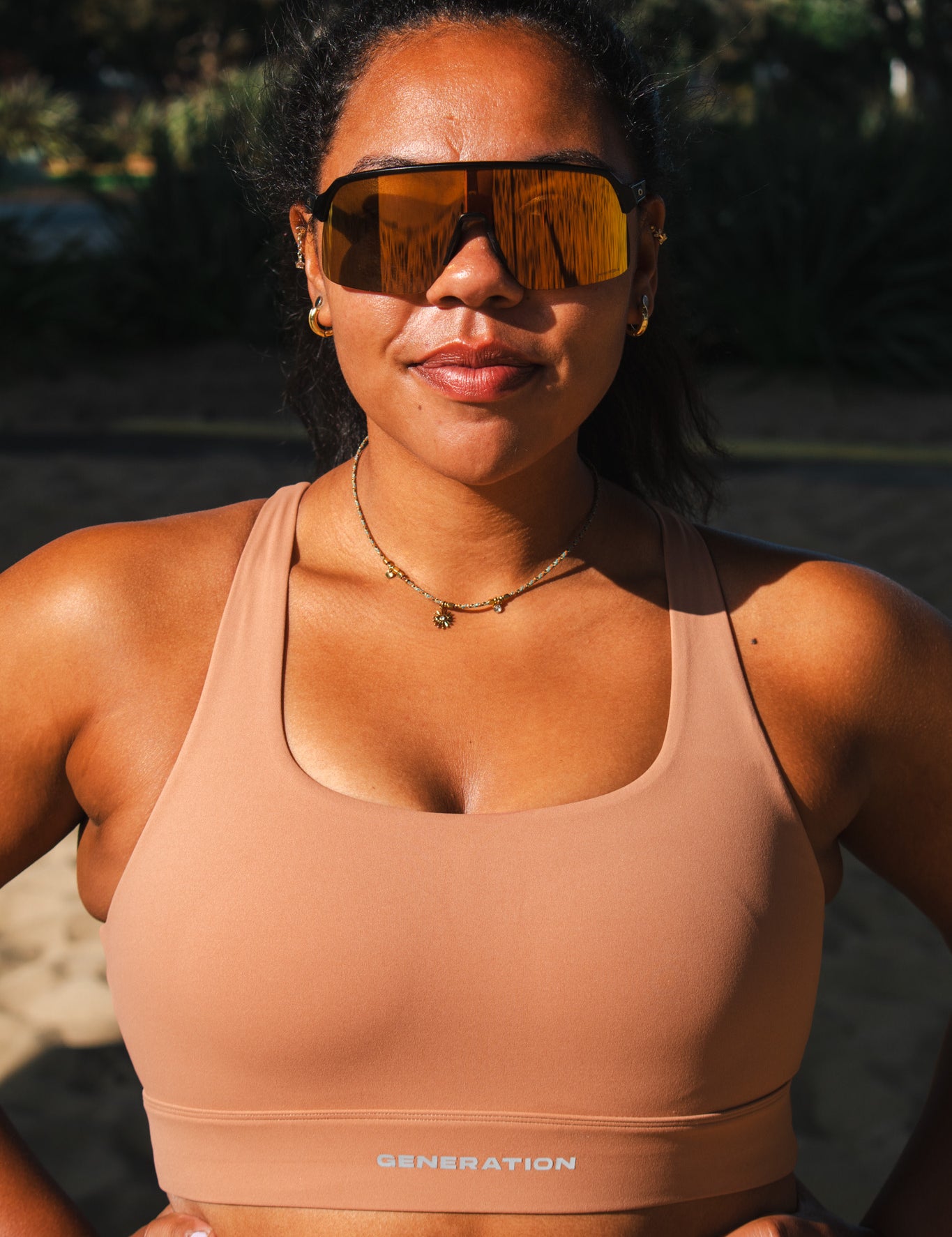 Woman wearing a beige sports bra with branding, standing outdoors.
