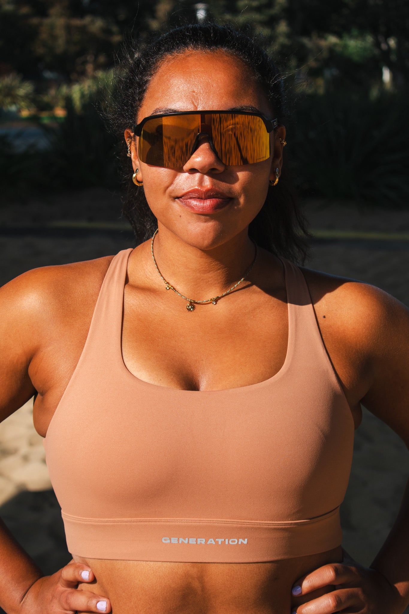 Woman wearing a beige sports bra with branding, standing outdoors.