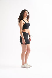 Side profile of woman in Assist High Rise Shorts with arms crossed, showing compression fit and clean seams.