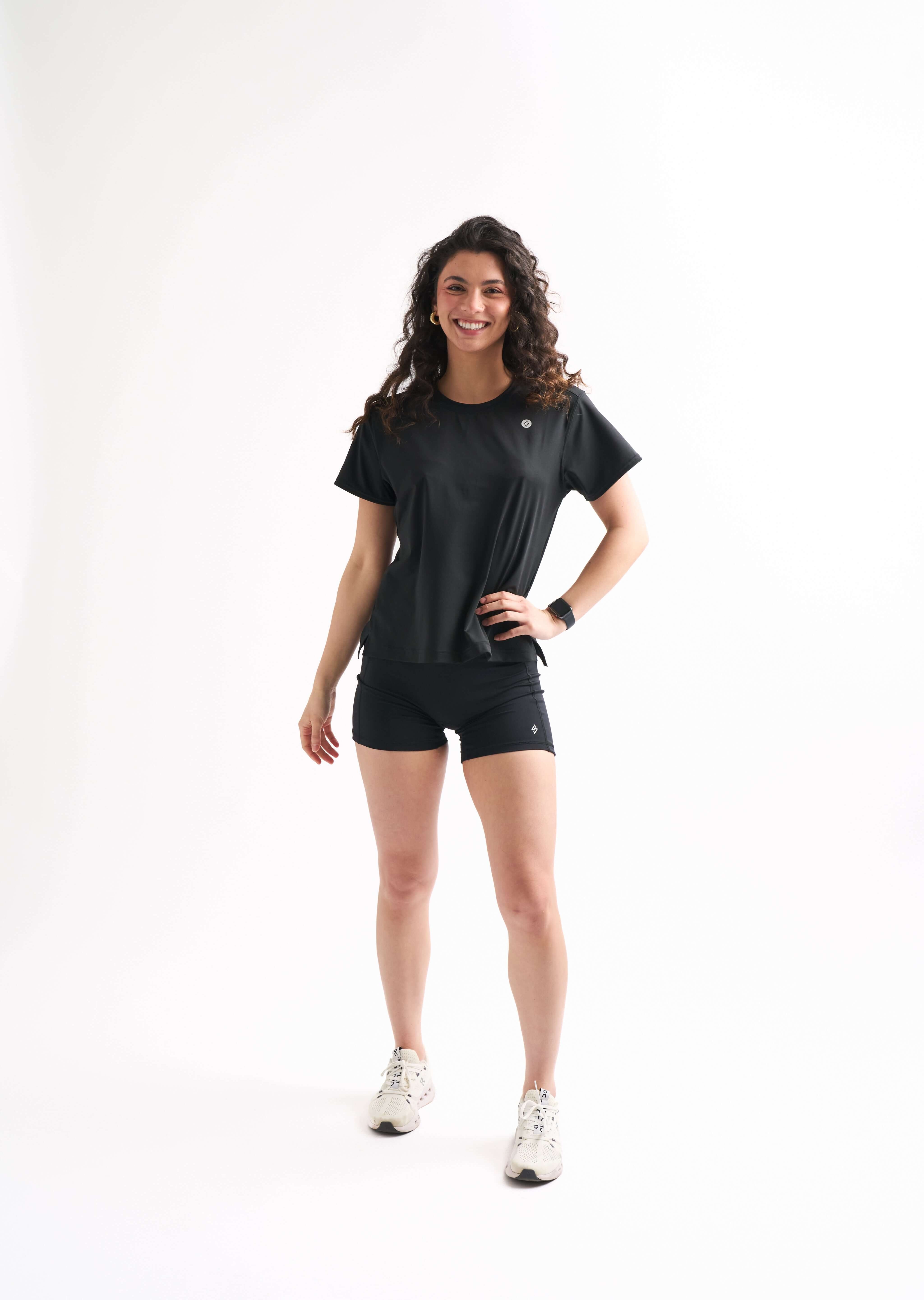 Woman standing at a slight angle with one hand on her hip, wearing the Flow State top and bike shorts.