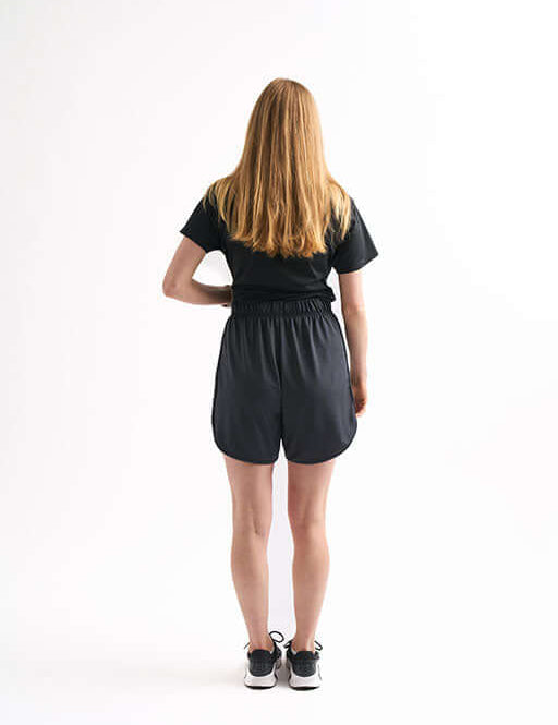 Back view of woman in Locked In Running Shorts with comfortable waistband and tee, styled for practice or running.