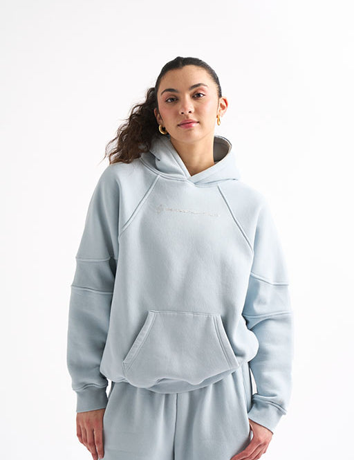 Woman in a light blue oversized sweat set with hands by her sides, showing the roomy fit of the hoodie and joggers