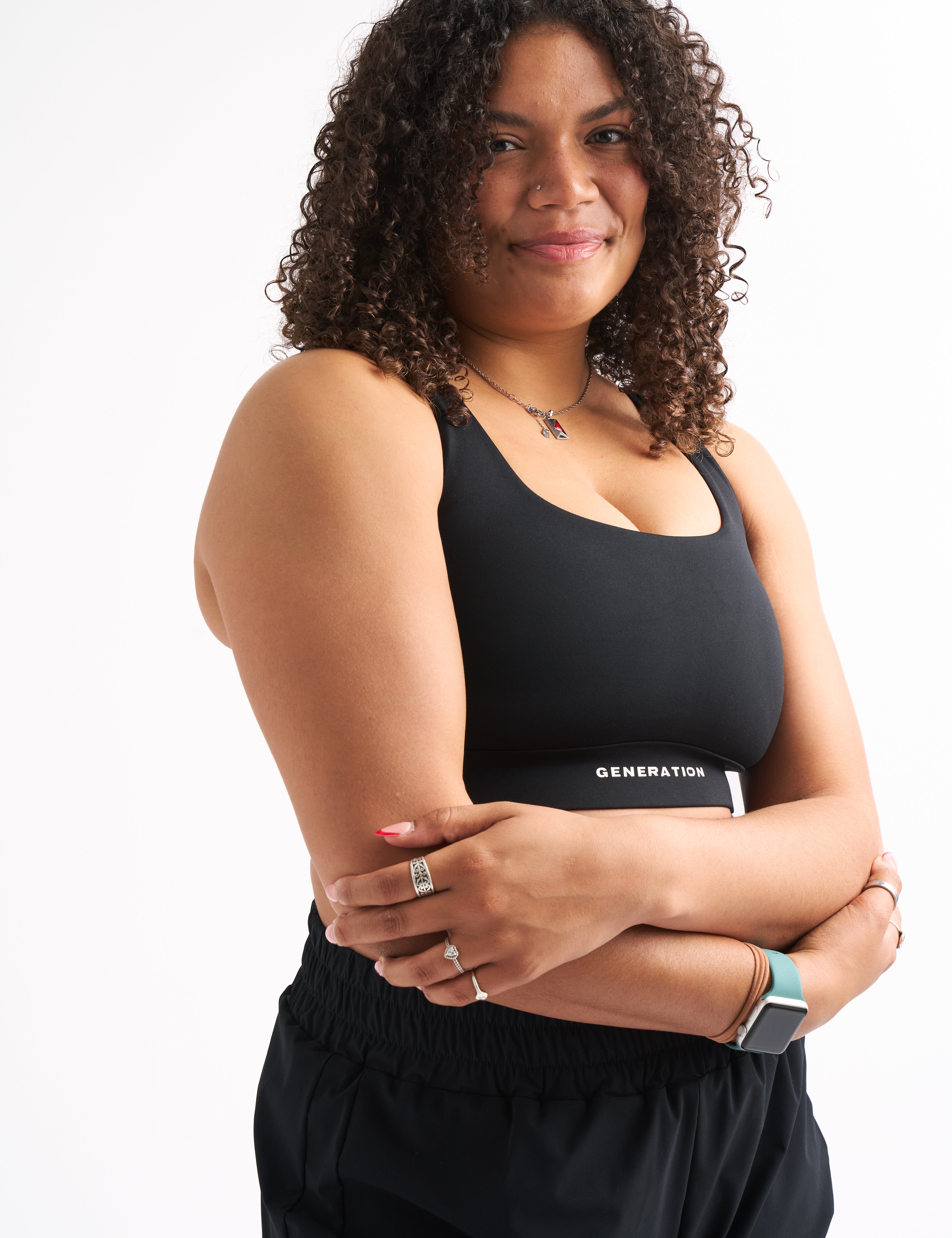 Close-up of a woman in a black ZERO G sports bra with arms crossed, showing supportive fit and smooth fabric.