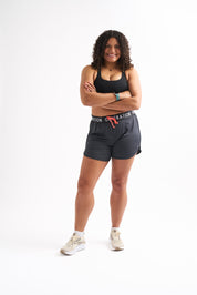 Cheerful woman wearing Locked In drawstring running shorts, showcasing comfort and style for active wear.