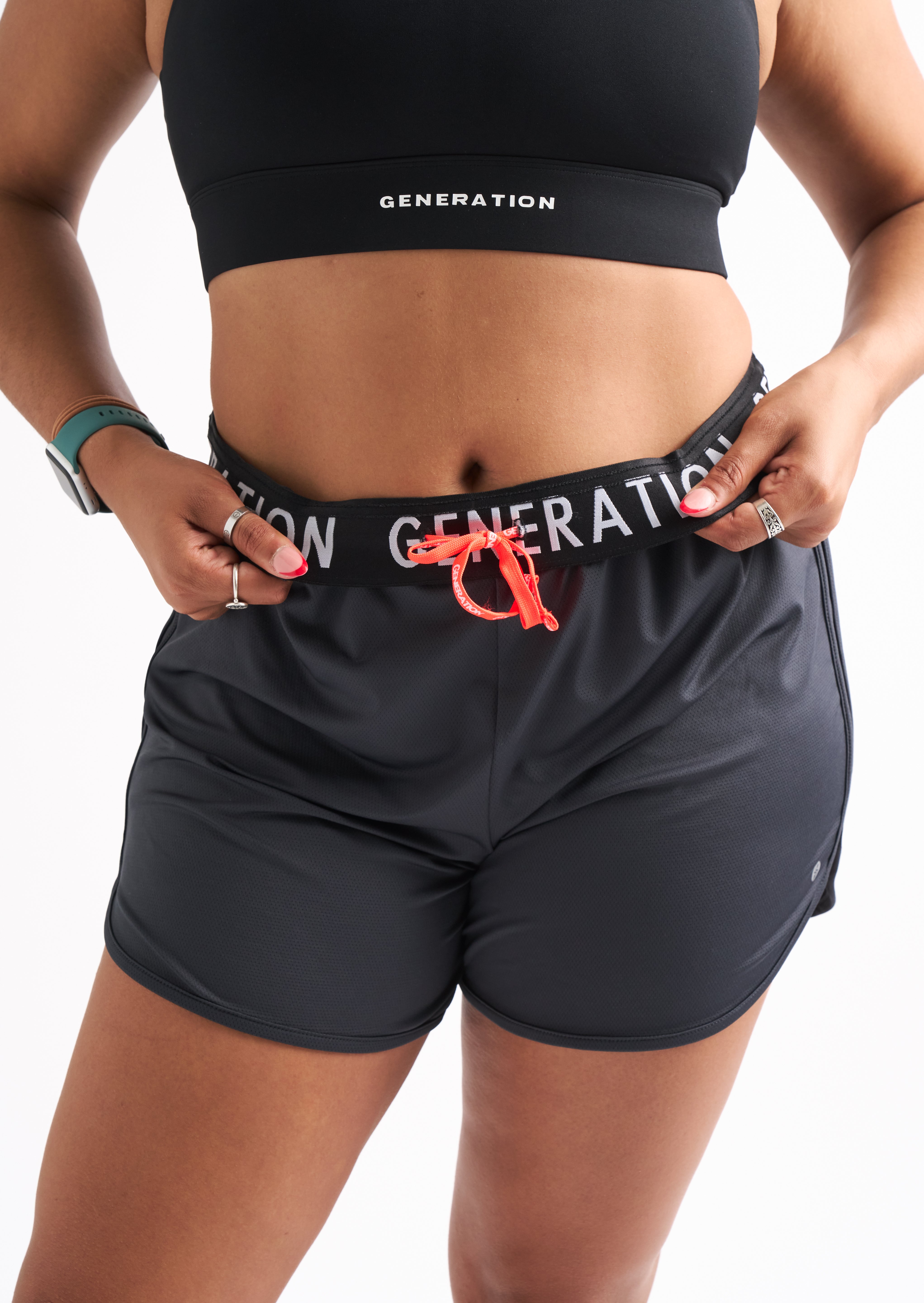 Close-up of woman wearing Locked In running shorts with foldable waistband and visible Generation Sport logo.