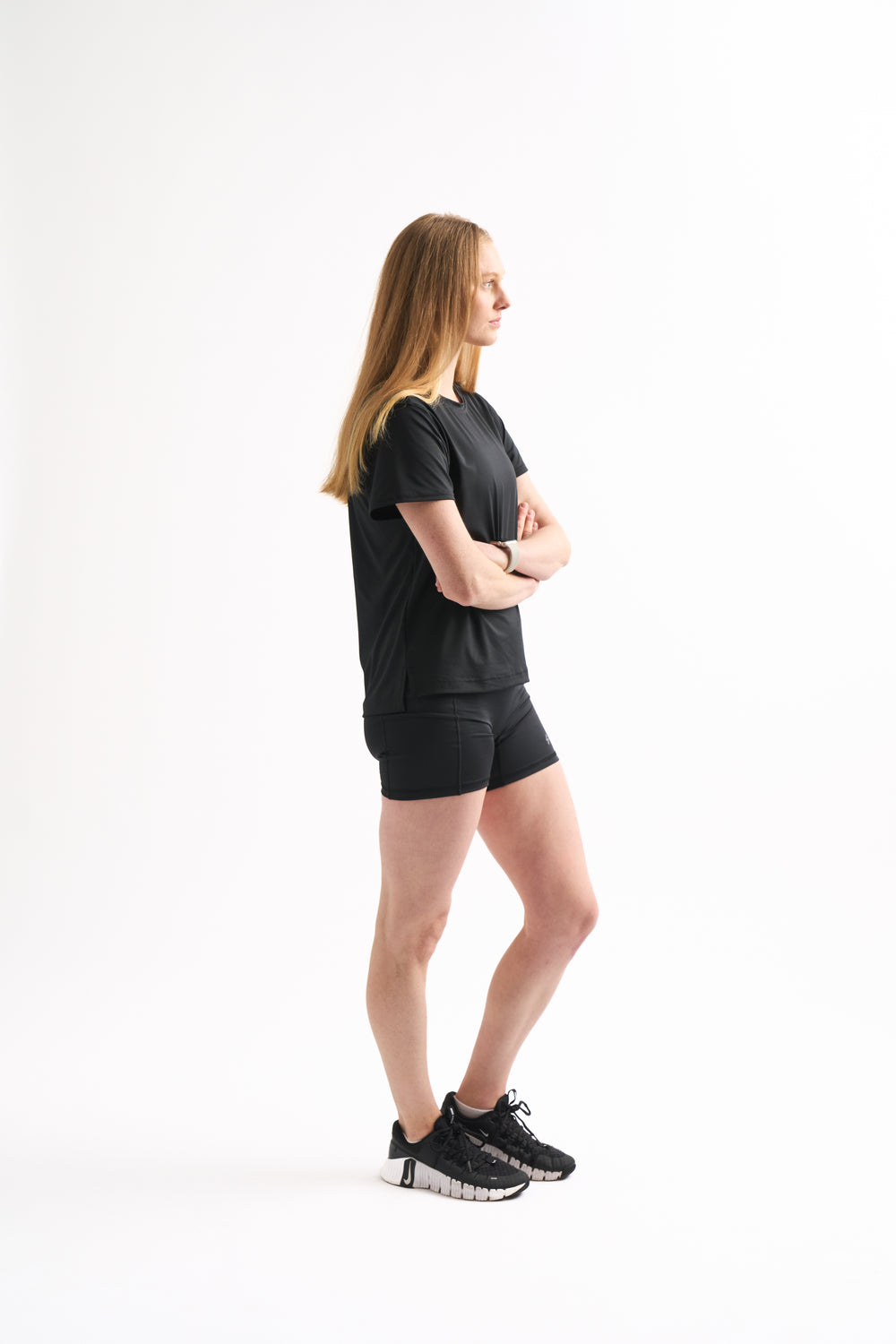 Side profile of woman in Assist High Rise Shorts with arms crossed, showing compression fit and clean seams.