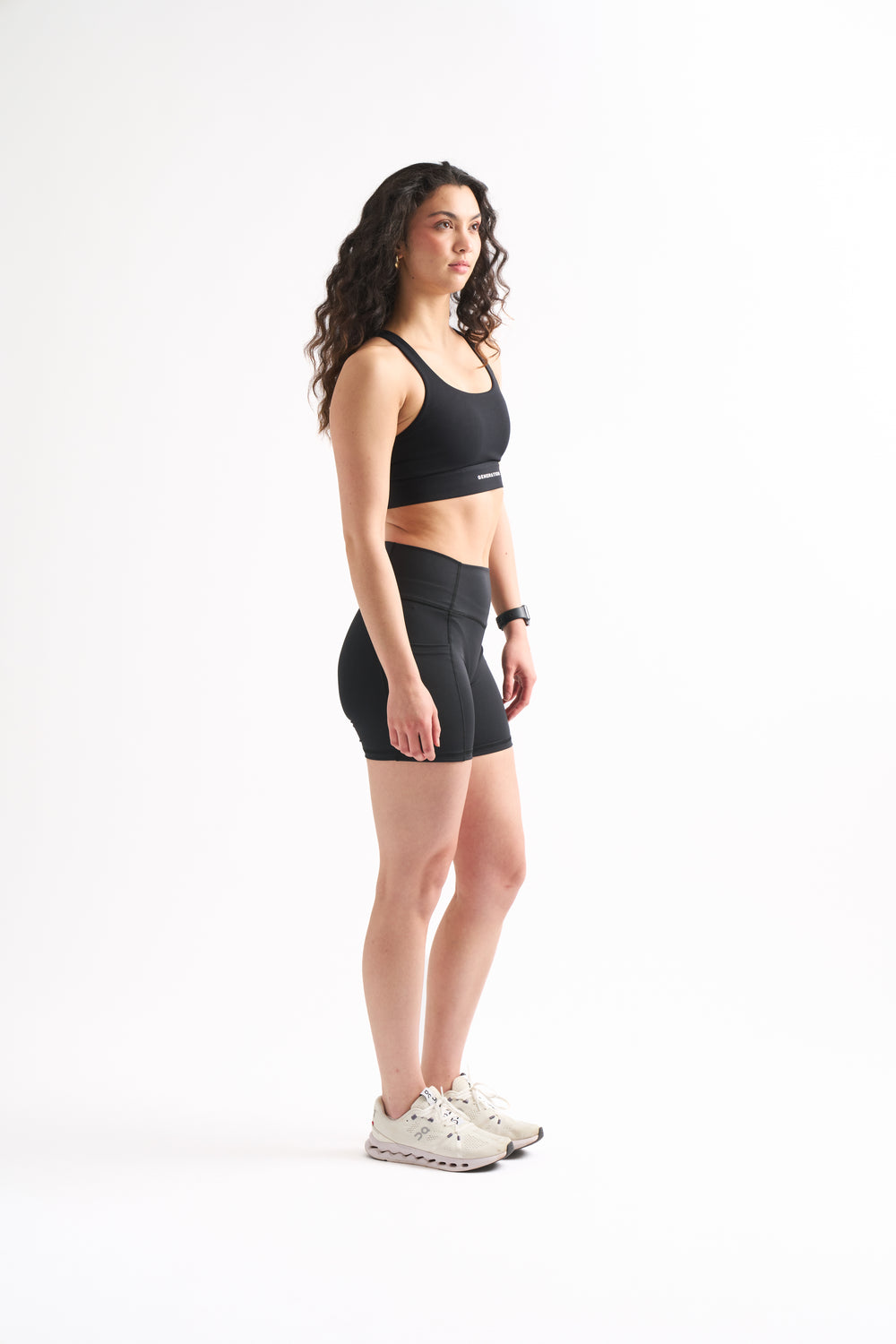 Side profile of woman in Assist High Rise Shorts with arms crossed, showing compression fit and clean seams.