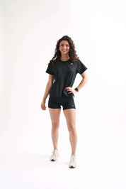 Woman standing at a slight angle with one hand on her hip, wearing the Flow State top and bike shorts.