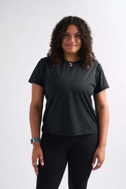 Woman smiling straight at camera wearing the Flow State top paired with full-length leggings.