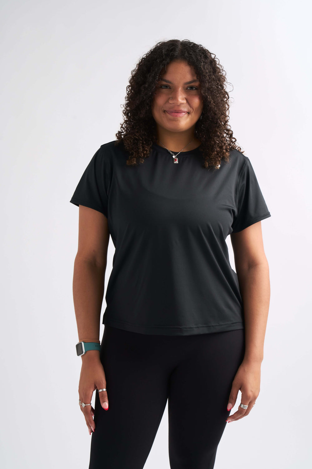 Woman smiling straight at camera wearing the Flow State top paired with full-length leggings.