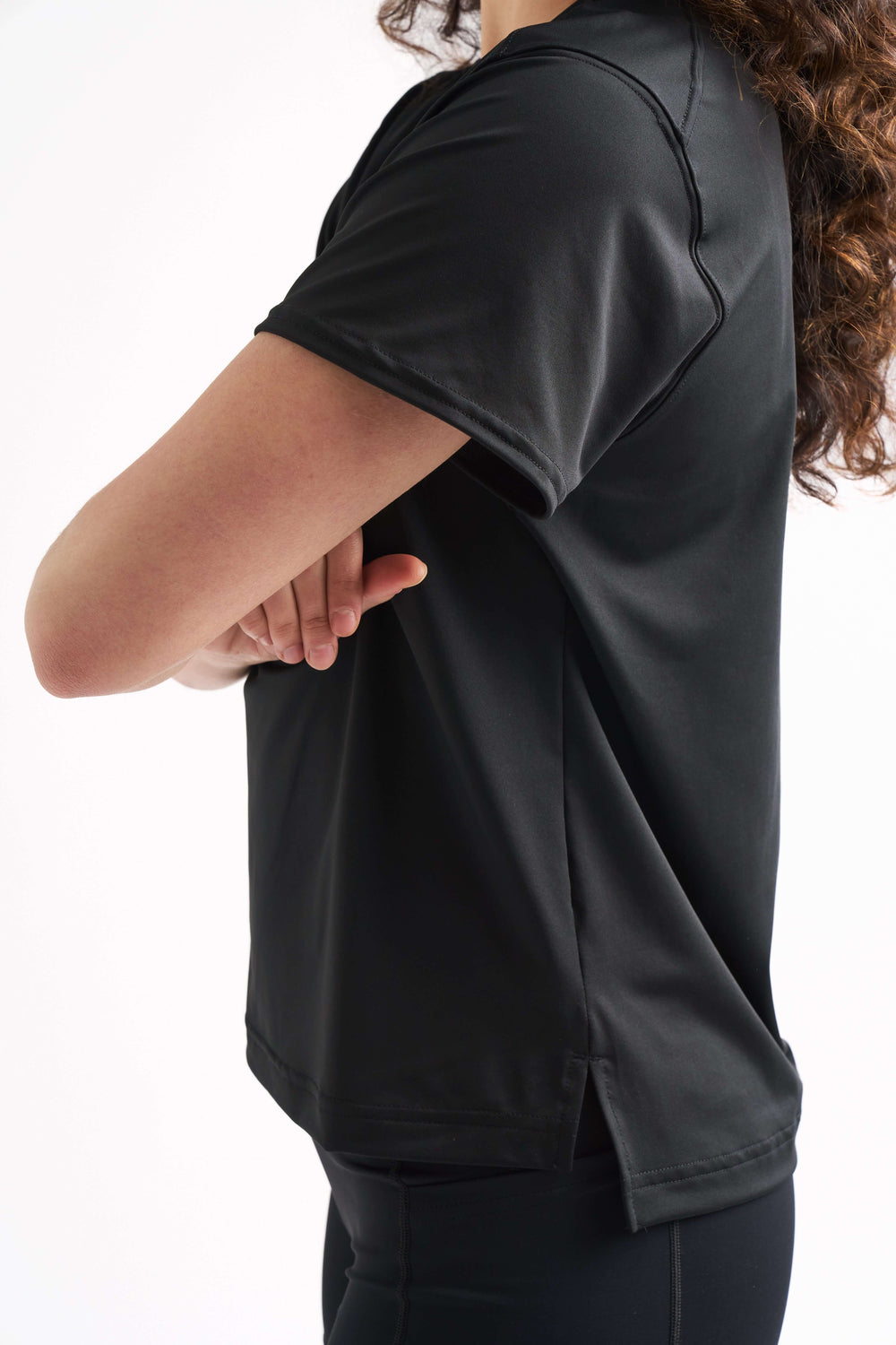 Close-up side view of a woman with arms crossed, highlighting the sleeve and fit of the Flow State top.