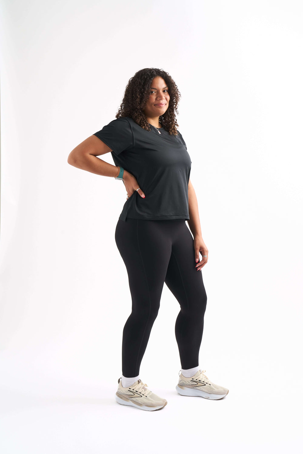 Woman standing with one leg bent and hand on her hip, wearing the Flow State top and shorts, smiling slightly.