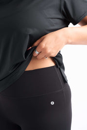 Close-up of stay-put waistband on buttery soft leggings as woman lifts her shirt.