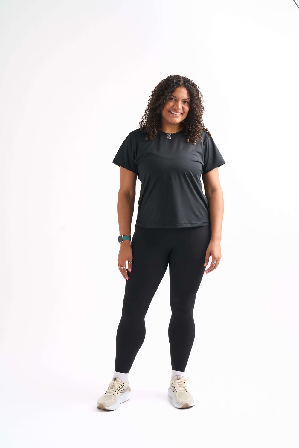 Woman standing with hands relaxed at sides, wearing Groundwork High-Rise Leggings and Flow State top with a confident smile.