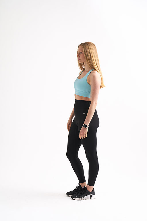 Side view of woman in Groundwork Highrise Leggings and blue longline sports bra.