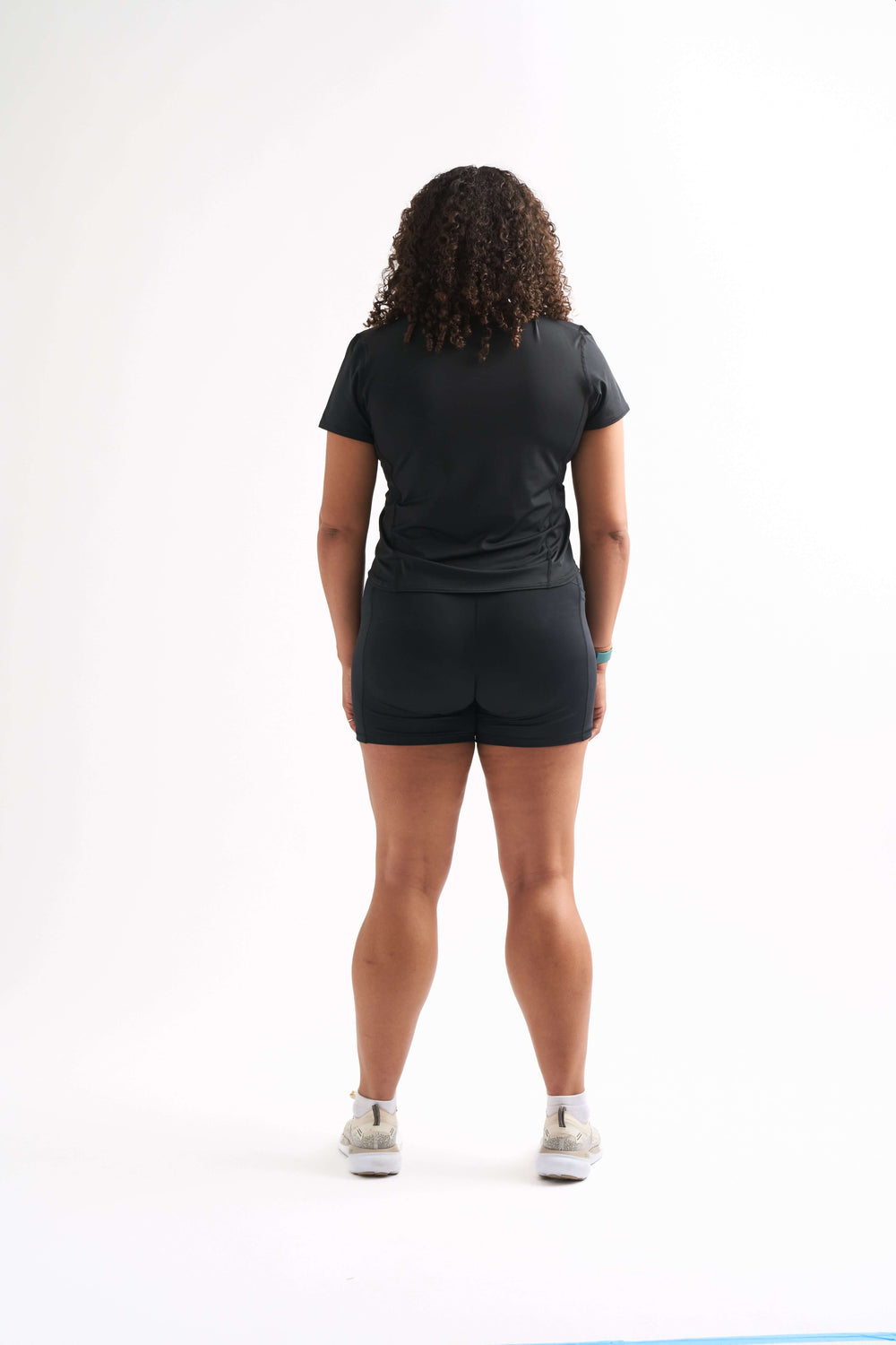 Back view of a woman in a fitted workout shirt and shorts, showcasing breathable fabric and curve-hugging fit.