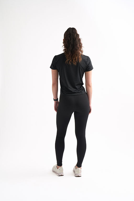 Woman from behind wearing a fitted workout shirt and leggings, showcasing a curve-hugging fit and breathable fabric.
