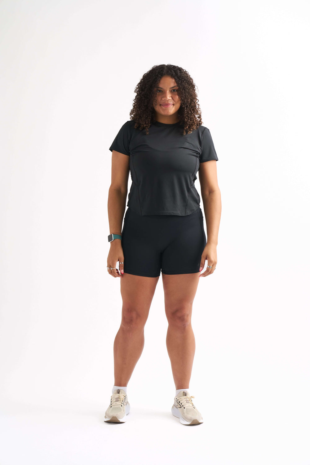 Model wearing a women's fitted workout shirt and shorts, showcasing a curve-hugging fit, perfect for gym sessions.