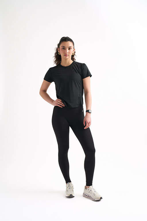 Woman in a fitted workout shirt and leggings, showcasing a curve-hugging fit and breathable fabric for gym performance.