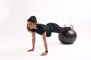 Woman in fitted workout shirt doing plank exercise on a stability ball, showcasing active lifestyle and performance gear.
