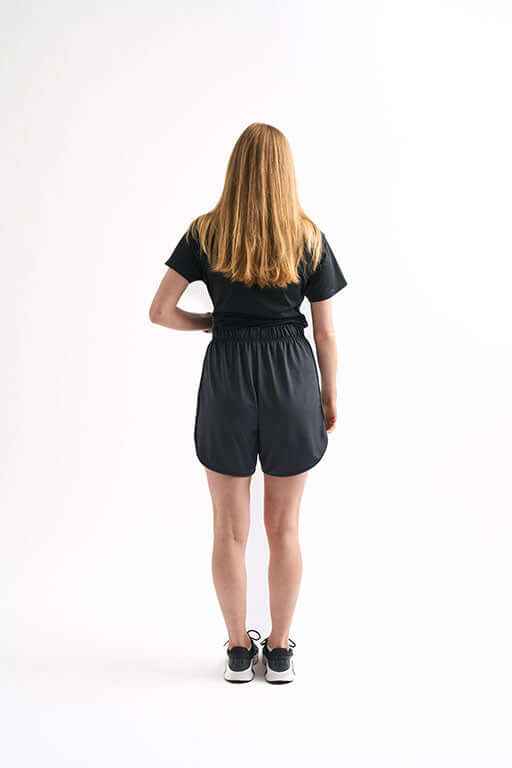 Back view of woman in Locked In Running Shorts with comfortable waistband and tee, styled for practice or running.