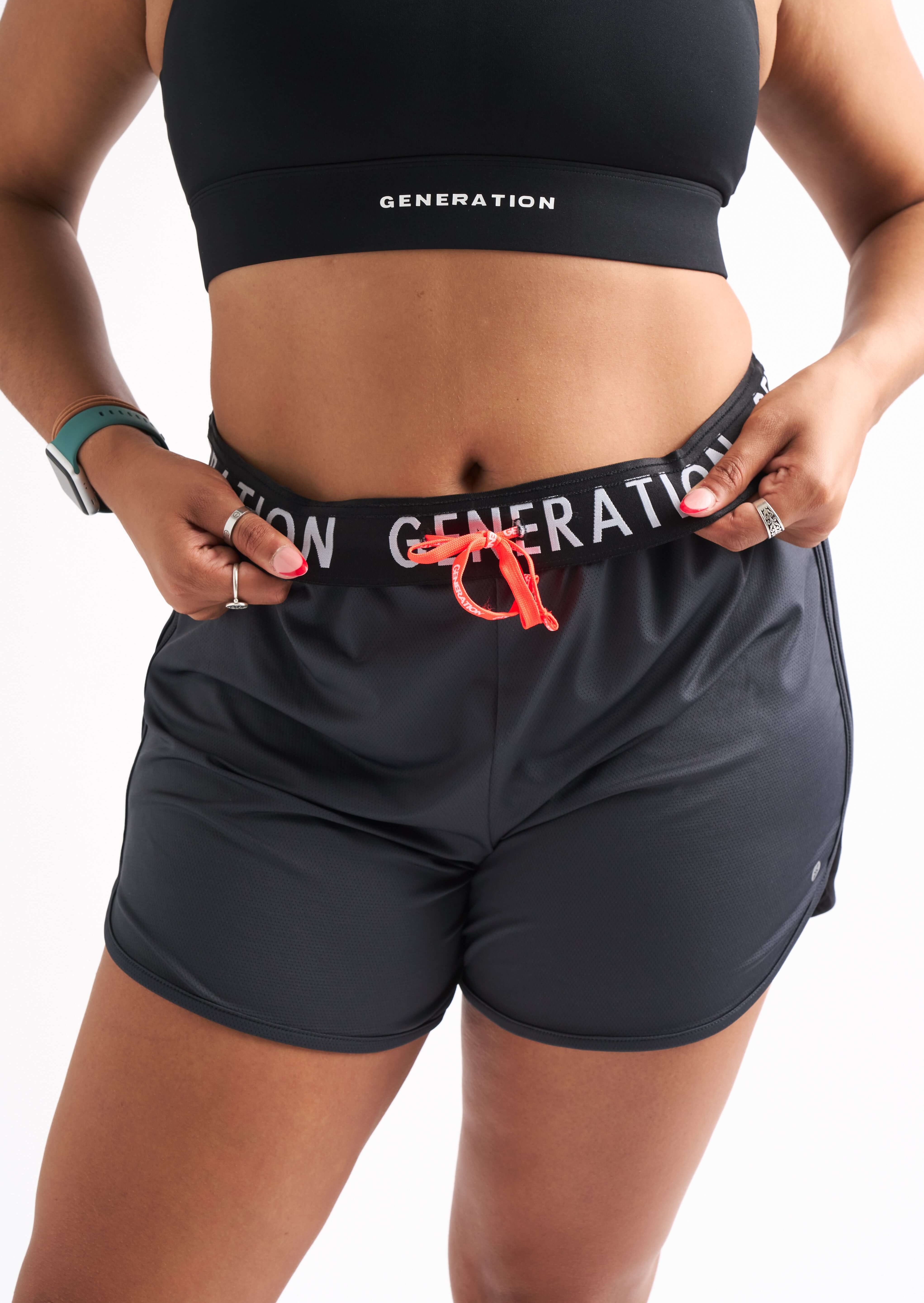 Close-up of woman wearing Locked In running shorts with foldable waistband and visible Generation Sport logo.