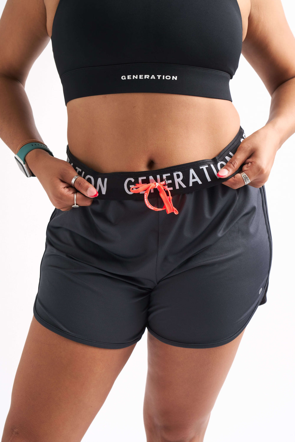 Close-up of woman wearing Locked In running shorts with foldable waistband and visible Generation Sport logo.