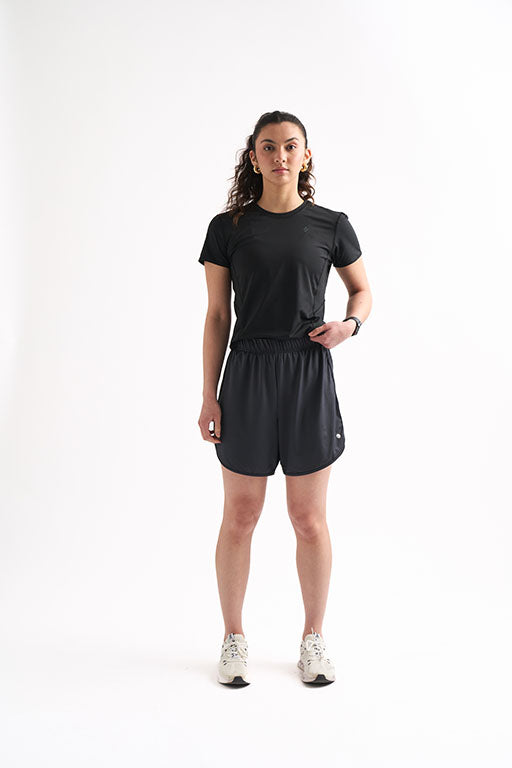 Woman wearing Locked In Running Shorts and a fitted T-shirt, standing with one hand on her hip.