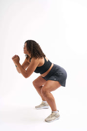 Woman squatting in breathable running shorts, showcasing style and comfort during workouts.