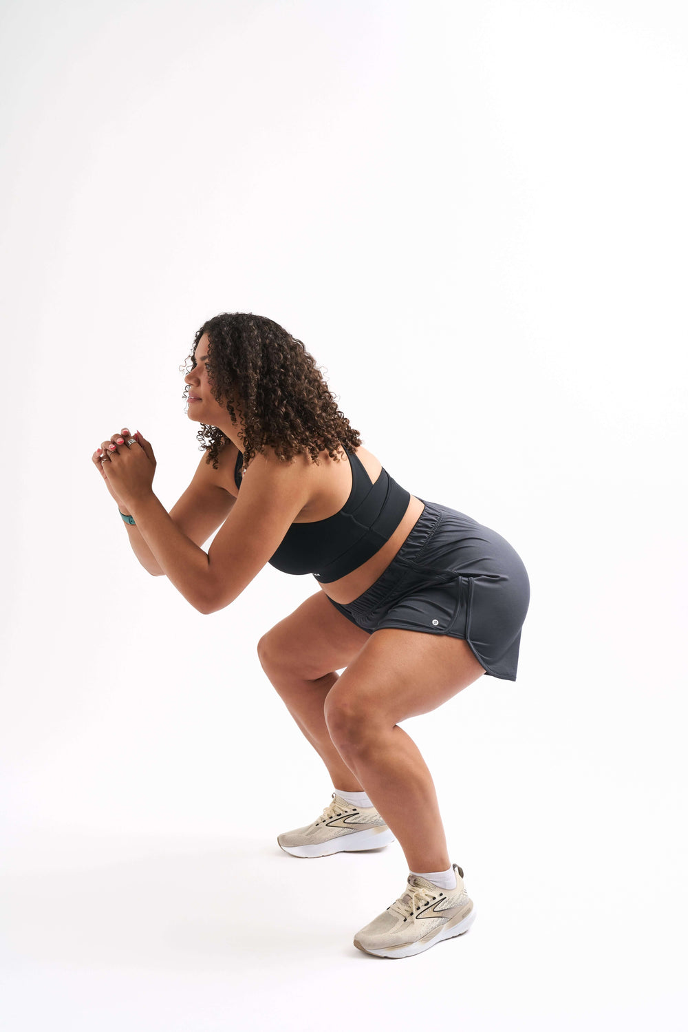 Woman squatting in breathable running shorts, showcasing style and comfort during workouts.