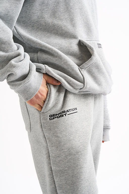 Close-up of woman's hand in jogger pocket, showing Generation Sport logo on fleece-lined sweatpants and hoodie.