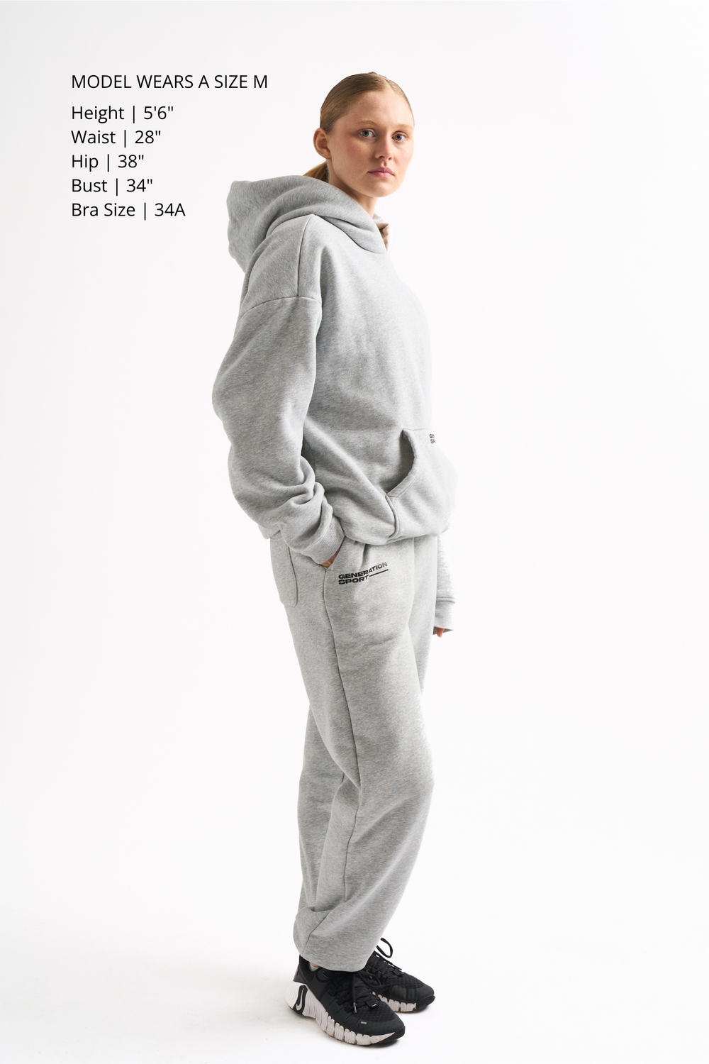 Side profile of woman in light gray cozy loungewear set showing hoodie length and jogger fit.