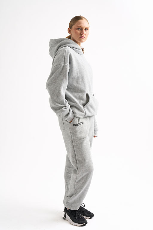Side profile of woman in light gray cozy loungewear set showing hoodie length and jogger fit.