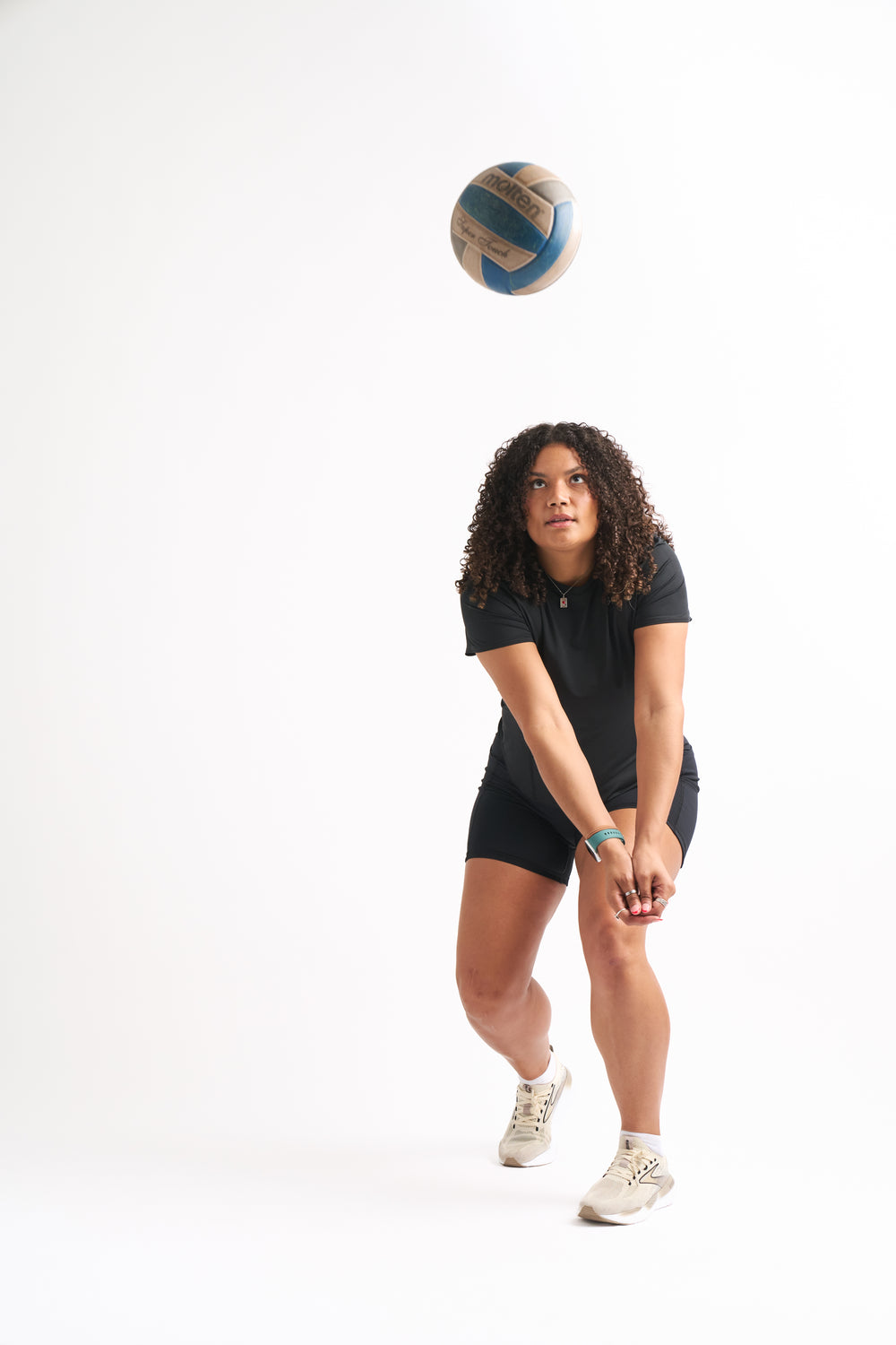 Model prepares to bump a volleyball while wearing Power Moves Midrise Shorts and a black tee.