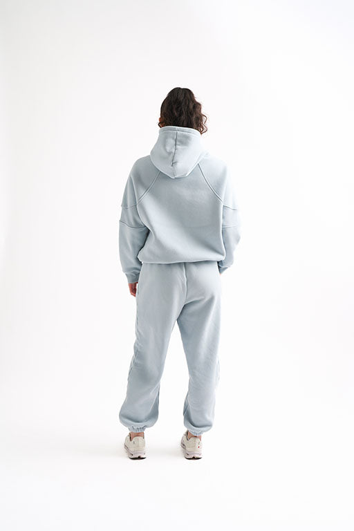 Back view of woman wearing a light blue oversized sweat set, showing the slouchy fit of the hoodie and joggers.